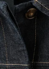 Chaqueta de algodón estilo tejano vaquero color azul marino oscuro, con pespuntes en contraste, cuello camisero, cierre frontal de botones y dos bolsillos delanteros de parche.
