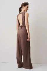 Pantalón de tiro alto color chocolate, con pinzas frontales que aportan caída suave y silueta amplia de pierna recta. Cierra con botón y bragueta, y suma un detalle de botón funcional en la cintura que le da un aire sastrero.