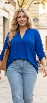 Blusa azul francia de viscosa y lycra, de corte holgado y diseño oversize, con escote en V y cuello estilo túnica. Cuenta con mangas largas con presilla y botón para arremangar.