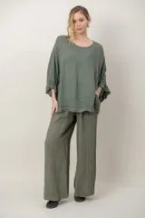 Blusa de lino color verde militar, holgada, de manga 3/4 con volados en los puños, cuello redondo y detalle de alforzas horizontales en el dobladillo.