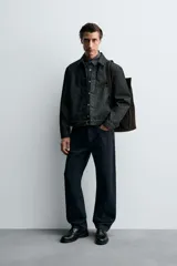 Cazadora de denim de algodón en color negro, de corte regular fit, con cuello solapa, cierre frontal de botones metálicos, mangas largas con puños abotonados y bolsillos laterales de vivo.