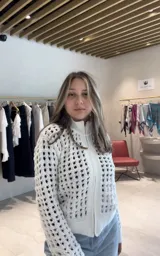 Chaqueta de punto con cierre frontal, cuello alto y diseño calado en color blanco.