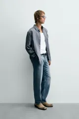 Camisa de corte relajado confeccionada en tejido fluido con mezcla de viscosa, presenta un diseño de rayas verticales, cuello solapa, cierre frontal con botones, manga larga con puño abotonado y un bolsillo de plastrón en el pecho.
