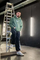 Canguro verde militar con capucha, estampado con texto en el frente y costuras a la vista.