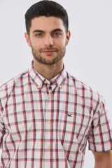 Camisa de manga corta a cuadros en tonos blanco, azul y gris, con cuello abotonado, bolsillo en el pecho y cierre frontal con botones.