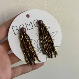 Par de aros colgantes con cuentas tubulares color cobre y cuentas redondas color marrón.