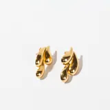 Aros colgantes dorados con forma de hojas estilizadas.