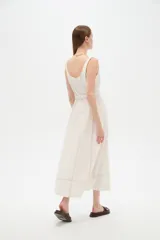 Vestido midi de lino color beige con diseño a cuadros discretos, cuello cuadrado, sin mangas y con cinturón ajustable en la cintura.