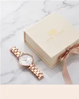 Reloj analógico de mujer con caja redonda y malla de eslabones en tono oro rosa. Presenta una esfera minimalista con índices lineales y movimiento de cuarzo japonés.