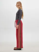 Pantalón ancho y suelto de tejido tipo terciopelo color naranja, con cintura elástica y cordón ajustable. Presenta detalles de pespuntes decorativos a los lados.