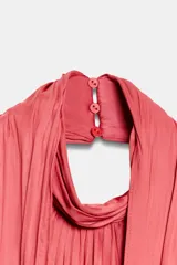 Top de cuello halter con diseño drapeado en el frente y cierre posterior con botones.