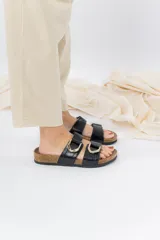Sandalias de cuero negro con tiras cruzadas y hebillas metálicas doradas. Base anatómica de corcho y goma antideslizante.