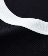 Musculosa negra de ribana con cuello redondo y sisas con ribete blanco en contraste.