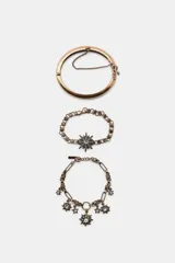 Set de tres pulseras metálicas de color dorado envejecido con detalles de brillos y dijes de estrellas.