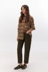 Camisa de manga larga con estampado de tapiz en tonos marrones, verdes y beige. Tiene cuello clásico y cierre frontal con botones.