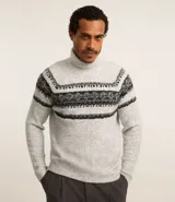 Suéter de punto gris con cuello alto y manga larga. Presenta textura jacquard y estampa horizontal étnica en tonos negros y grises.