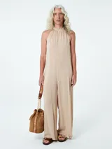 Mono color beige con cuello halter y corte palazzo.