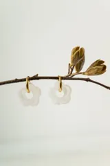 Aros tipo argolla dorada con dije colgante en forma de flor de resina blanca traslúcida.