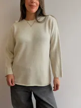 Sweater de punto de diseño minimalista, color beige, con cuello redondo y mangas largas. Presenta un corte recto y holgado con acabado liso.