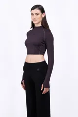 Remera cropped de manga larga con cuello alto, confeccionada en tejido elástico color negro. Presenta costuras visibles y un pequeño logo aplicado en el centro del pecho.