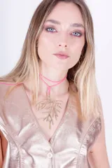 Collar con cordón rosa y dije colgante con forma de rama en color bronce.