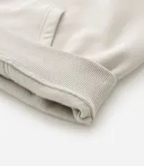 Saco con capucha color gris oscuro, con cordón ajustable, bolsillo canguro y mangas largas con puños ajustados. Confeccionado en algodón con felpa.