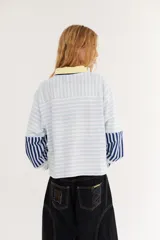 Remera de manga larga boxy de algodón con diseño de rayas horizontales celestes y rosadas, cuello polo bordó, detalles amarillos y logo bordado en el pecho.