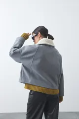 Campera corta de paño color gris con cuello de corderito blanco, cierre frontal con botones y bolsillos laterales.