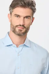 Camisa de vestir blanca de corte clásico, con mangas largas, cuello camisero y cierre frontal de botones.