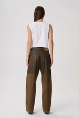 Jean baggy de tiro medio con efecto desgastado y acabado degradé en tonos tierra. Silueta amplia y recta en denim tratado a mano.