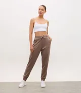 Pantalón tipo jogger de mujer, confeccionado en tejido modal con mezcla de poliéster y elastano. Presenta cintura elástica con lazo de ajuste, bolsillos laterales y puños elásticos en el ruedo.