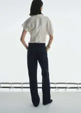 Jeans de tiro alto y corte recto, confeccionados en tejido de algodón estilo tejano vaquero en color azul oscuro con lavado rinse. Presentan cierre frontal con cremallera y botón, trabillas para cinturón y diseño clásico de cinco bolsillos.