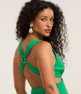 Vestido midi de algodón color verde esmeralda con diseño de laser cut y recortes en la cintura. Presenta escote en V profundo y tirantes finos que se cruzan en la espalda con esferas decorativas.