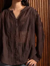 Blusa de tela liviana color bordó, con escote en V y detalles de bordado floral tono sobre tono. Presenta mangas largas con leve volumen y puños abotonados.