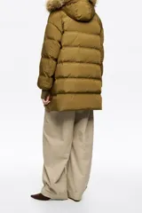 Campera puffer de largo medio en tejido técnico color verde oliva, con cierre frontal de cremallera y botones a presión. Cuenta con capucha con borde de pelo sintético desmontable, bolsillos laterales con cremallera y puños tejidos ajustados.
