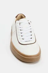 Zapatillas deportivas de color blanco con detalles en marrón y suela de goma color tostado. Cierre con cordones y puntera redonda.