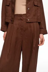 Pantalón de lino color marrón de corte recto y tiro medio, con bolsillos laterales y pinzas delanteras.