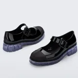 Mocasín estilo Mary Jane de la marca Melissa, modelo June Ad, confeccionado en material sintético negro con acabado brillante. Cuenta con tira ajustable en el empeine con hebilla gruesa, puntera reforzada en tono mate y suela translúcida de goma con diseño chunky.