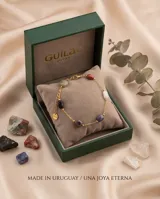Pulsera de cadena fina con baño de oro, adornada con tres piedras naturales de distintos colores y formas irregulares distribuidas a lo largo de la cadena.