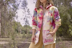 Canguro con capucha y cierre frontal, color beige con estampado de hojas en tonos marrones y amarillos. Mangas largas en color gris.