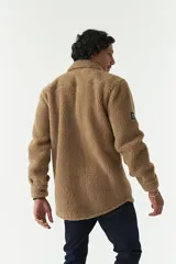 Sobrecamisa de sherpa color crema con cuello camisero, cierre frontal con botones a presión y bolsillo de parche en el pecho. El modelo usa talle M.