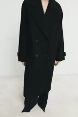 Abrigo largo de corte oversize con cuello de solapa, manga larga y cierre frontal cruzado con botones. Cuenta con bolsillos delanteros.