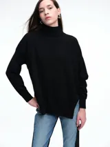 Sweater de tejido de punto color negro con cuello alto, corte amplio y tajos laterales en el ruedo, siendo la parte trasera ligeramente más larga.