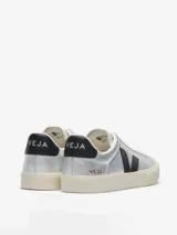 Zapatilla Veja modelo Campo, confeccionada en cuero bovino con acabado metalizado plateado. Presenta el logo de la marca en contraste negro en el lateral, detalle en el talón y suela de goma en tono crema.