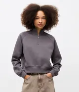 Buzo de algodón con felpa, de corte estructurado y diseño cropped. Presenta cuello alto con medio cierre frontal, mangas largas con puños elásticos y ruedo con elástico ancho.