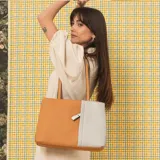 Cartera tipo tote de cuero sintético con diseño combinado en tono gris y blanco, textura granulada, asas largas para el hombro y cierre superior.
