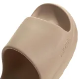 Chanclas tipo slide Adidas modelo Adilette Lumia, color marrón claro, con diseño ergonómico de una sola pieza, suela con ranuras flexibles y logo Adidas grabado en el lateral.