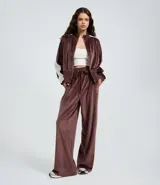 Pantalón wide leg de textura aterciopelada color bordó, con cintura elástica ajustable mediante lazo y franjas laterales en contraste.