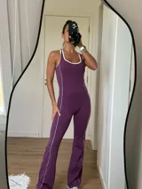 Mono enterito deportivo color violeta, con diseño ajustado al cuerpo, escote redondo y tirantes anchos tipo deportivo con recortes en color blanco.