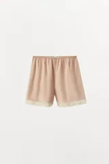 Shorts de tiro alto confeccionados en tejido satinado color beige, con cintura elástica y detalle de aplicación de encaje en el bajo.